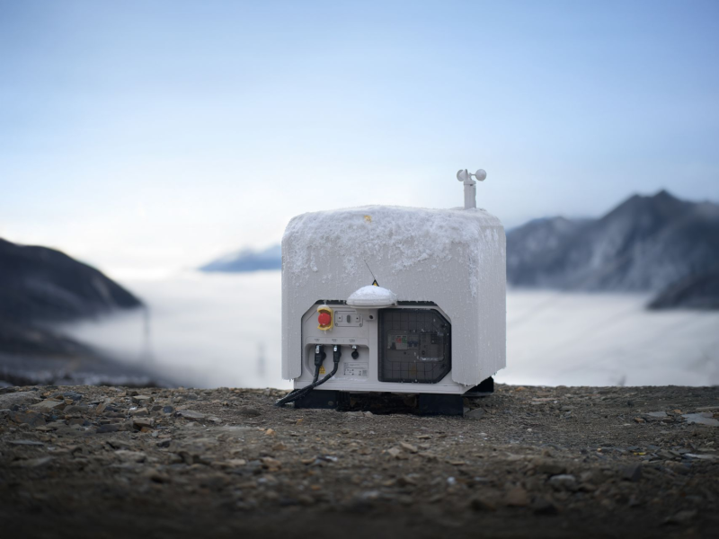 DJI Dock 3 covered in Ice on a rocky surface with mountains and fog in the background