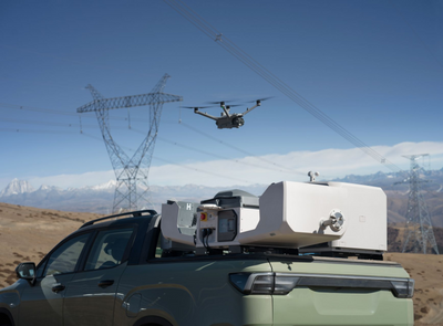 Drone flying over a vehicle with equipment on a mountainous landscape