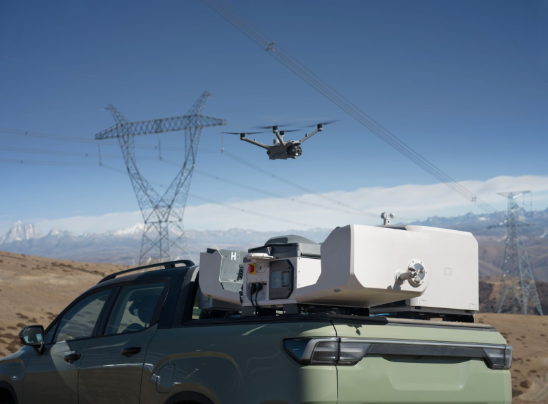 Drone flying over a vehicle with equipment on a mountainous landscape