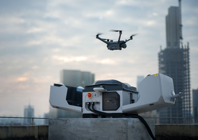 Drone flying above a DJI Dock 3 on a rooftop with city skyline in the background